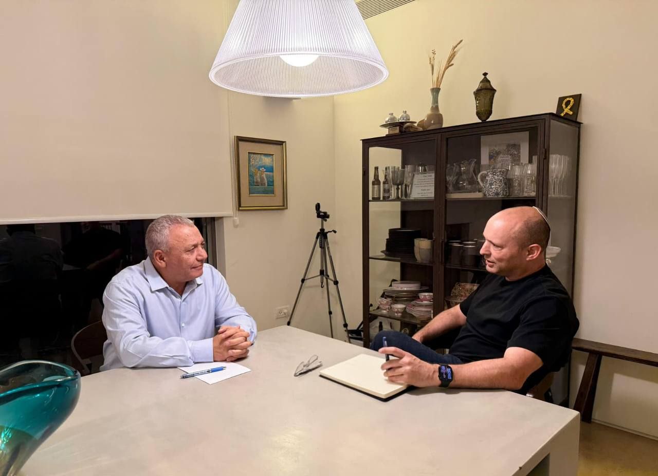 גדי איזנקוט ונפתלי בנט יושבים ליד שולחן ומשוחחים.