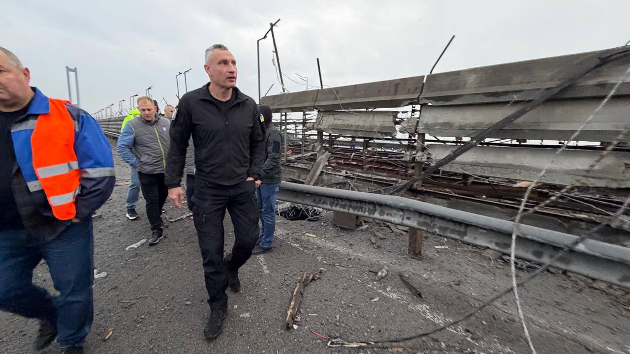 גברים הולכים על גשר לצד מעקות הרוסים וכבלים חשופים.